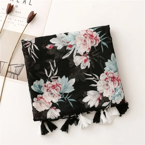 Detail of bohemian black scarf with pink floral patterns and fringe edges on white background