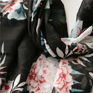 Detailed macro view of black voile scarf fabric featuring pink floral prints and fiber texture