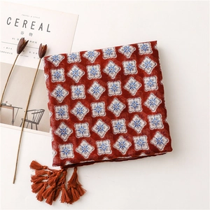 Détail d'une écharpe douce cramoisie avec motifs géométriques et pompons à franges