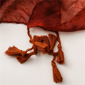 Détail d'une écharpe à carreaux rouge et marron avec glands tissés à la main et texture coton