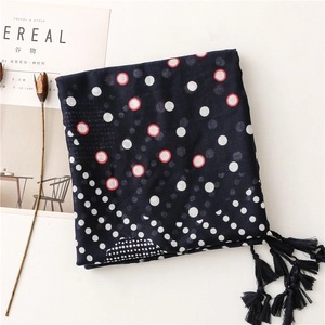 Detail of dark blue polka dot cotton scarf with fringe trim and lightweight texture