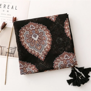 Détail d'une écharpe bohème noire à motifs cachemire avec des pompons délicats