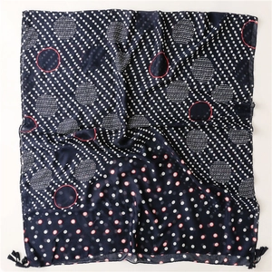 Detail of navy blue cotton linen scarf with white polka dots and delicate tassel fringe