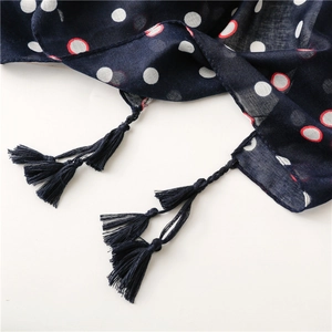 Detail of dark blue scarf with red and white polka dots and delicate tassel fringe edges