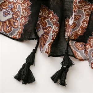 Détail de l'imprimé paisley bohème sur écharpe noire avec bords à franges glands