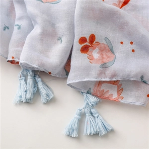 Détail d'une écharpe à fleurs avec pompons doux et texture de tissu léger et respirant