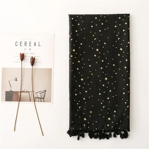 Close-up of black scarf with gold star moon prints and fringe tassels on white background