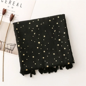 Detail of black cotton scarf featuring gold foil star and moon patterns with tassels
