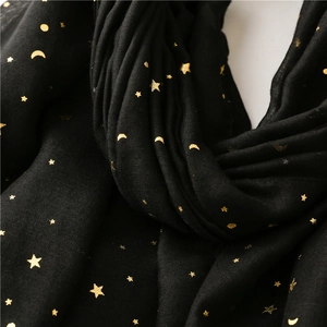 Detail of black cotton scarf featuring golden foil star and moon patterns with fine texture