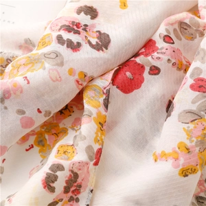 Detailed macro shot showing the floral print and soft cotton-linen texture of the scarf
