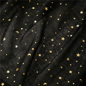 Close-up of gold foil star and moon patterns on delicate black cotton linen fabric
