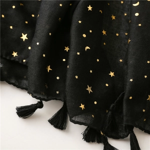 Detail of black cotton scarf featuring golden moon and star foil print with tassel fringe
