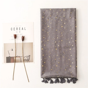 Detail of grey scarf with gold foil stars and moon patterns featuring tassel edges