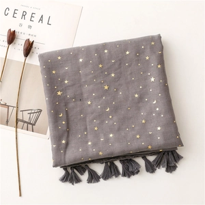 Close-up of dark grey scarf featuring gold foil star patterns and soft tassel fringe
