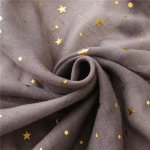 Detail of grey muslin scarf showing gold foil moon and star print with textured weave