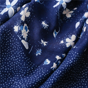 Detail of navy blue cotton linen scarf with white floral patterns and soft fabric texture