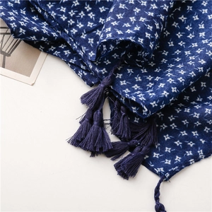 Detail of dark blue linen scarf with white star print and long decorative tassels