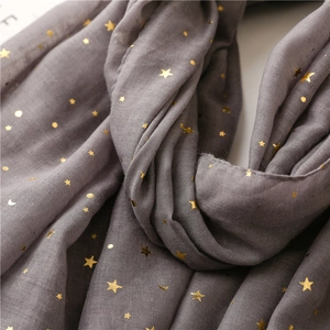 Macro shot of grey scarf with gold foil stars and moon pattern on woven fabric texture