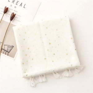 Detail of white cotton scarf featuring gold foil stars, moons and fringe tassels