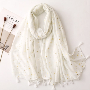 Close-up of white voile scarf featuring gold star prints and delicate tassel edges
