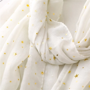 Close-up of white scarf fabric featuring gold foil star and moon patterns with soft texture