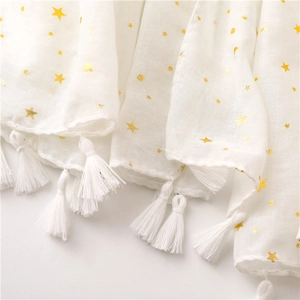 Close-up of white scarf with gold foil stars, moons and soft fringe tassel details