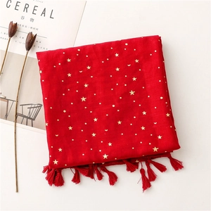 Close-up of red cotton scarf featuring gold star patterns and delicate fringe edge