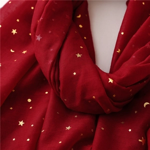 Detailed macro view of gold foil star and moon patterns on a red lightweight scarf fabric