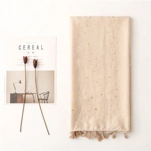 Detail of beige scarf featuring golden star patterns and elegant fringe tassels