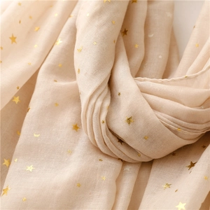 Close-up of beige linen scarf with gold foil star and moon patterns showing fabric texture