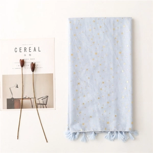 Macro detail of sky blue scarf featuring gold foil star moon prints and tassel fringe
