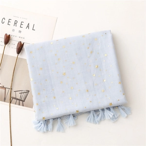 Close-up of light blue scarf with gold stars, fringes, and textured linen-feel fabric