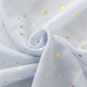 Macro view of light blue voile scarf featuring gold star and moon patterns with fringe