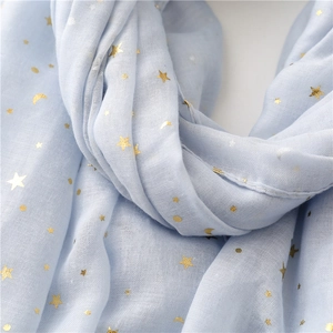 Close-up of light blue scarf with gold foil stars and moon patterns on breathable fabric