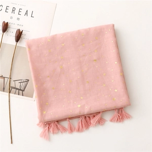 Macro shot of light pink cotton scarf with gold star moon prints and tassel fringe detail
