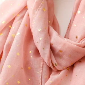Macro shot of pink scarf fabric with gold foil stars and moon patterns with soft fringe