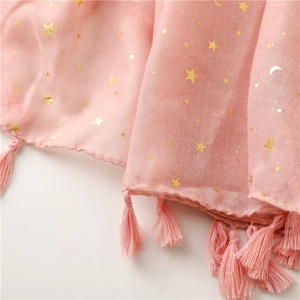 Close-up of pink bali yarn scarf with gold foil star and moon patterns and tassel fringe