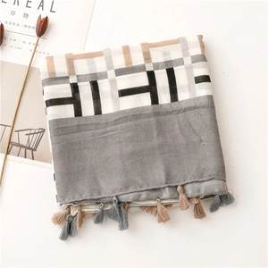 Detail of the geometric plaid scarf with tassel trim and soft neutral color blocking