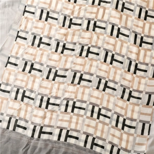 Detailed macro view of the repeating IF geometric letter pattern on light satin scarf fabric