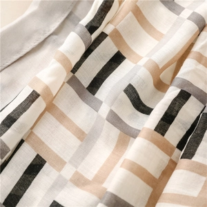 Macro detail of geometric checkered scarf showing cotton-linen texture and neutral tones