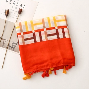Detail of folded cotton-linen scarf featuring geometric check pattern and orange tassels
