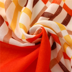 Detailed close-up of orange and yellow plaid satin scarf texture with soft fabric folds