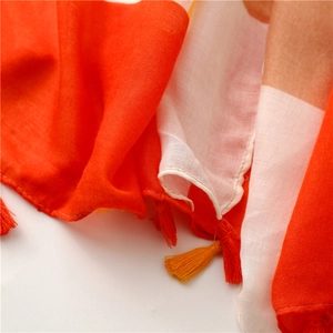 Detailed close-up of geometric pattern scarf featuring decorative orange and yellow tassels