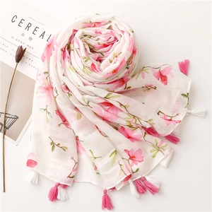 Detail of white linen scarf featuring pink floral print and handmade tassel edges