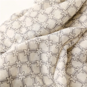 Close-up of lightweight satin scarf showing star patterns and soft fabric texture