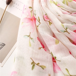 Detail of floral printed scarf with pink flowers and handmade fringe on white linen