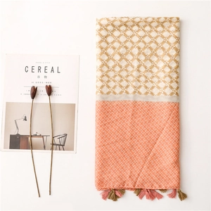 Detail of a two-tone geometric scarf with tassel accents and light cotton-linen texture