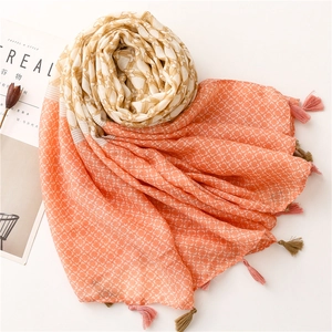 Detail of orange gradient scarf showing floral prints and delicate fringe tassels