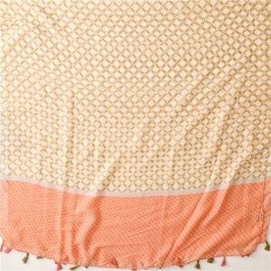 Detail of geometric star patterns and orange fringe tassels on a soft satin silk scarf