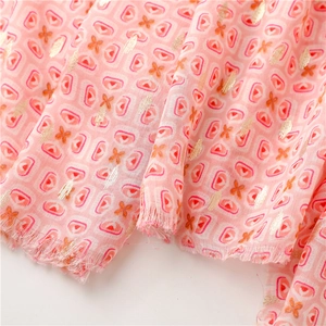 Detail of pink cotton-linen scarf with geometric gold foil prints and tassel edges